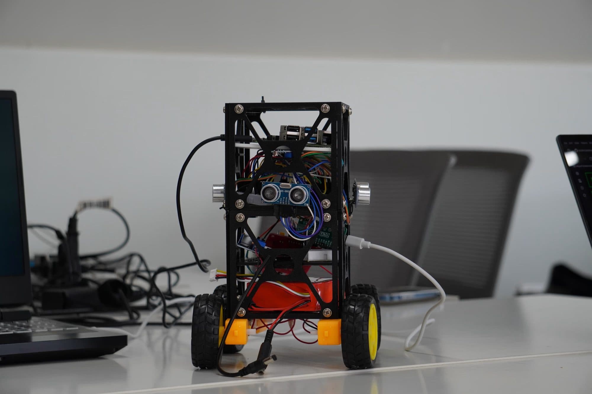 A wheeled robot build: stacked frame, ultrasonic sensors and hand-wired boards.