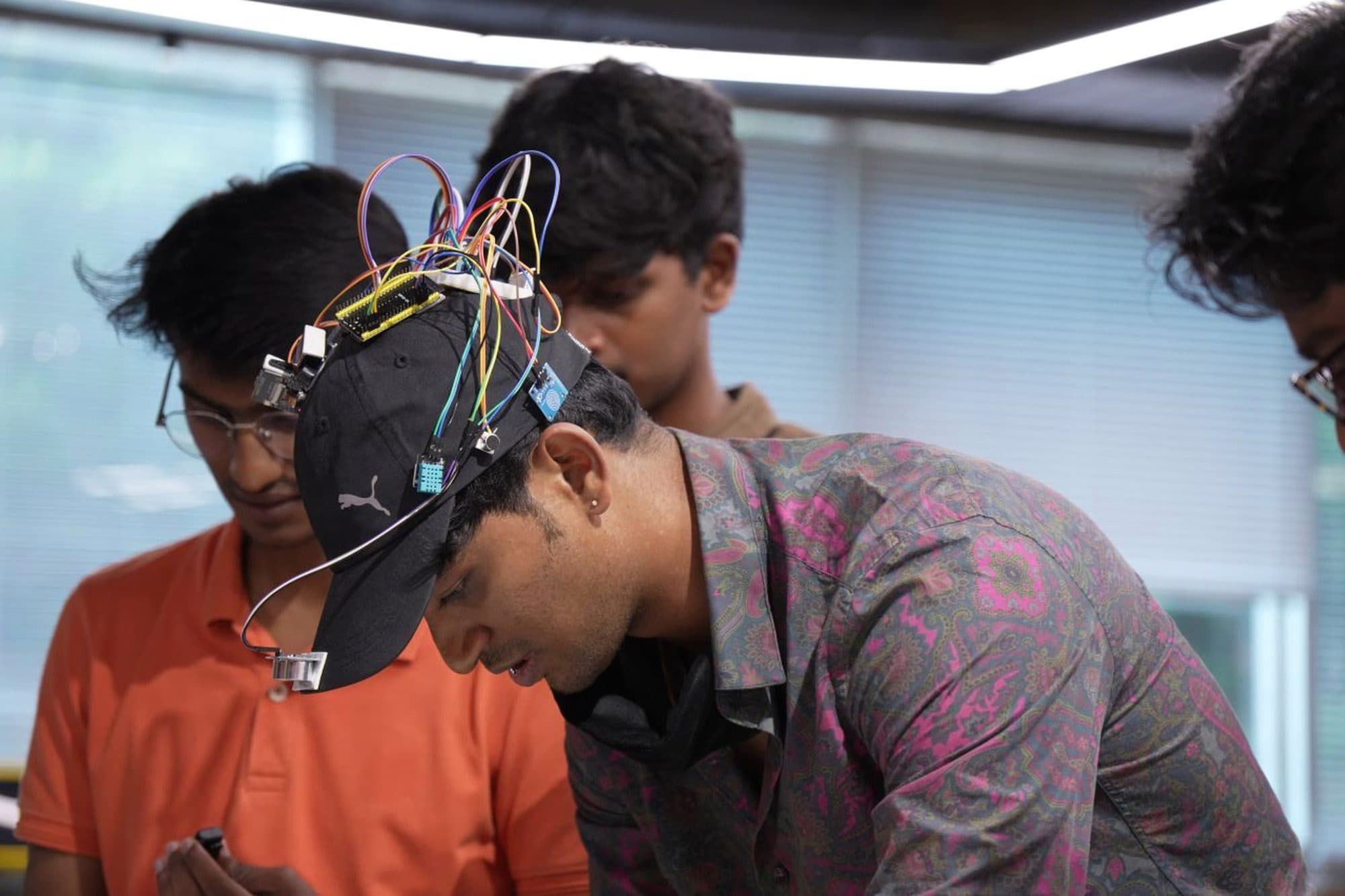 A wearable prototype: sensor modules and a microcontroller board wired onto a cap.