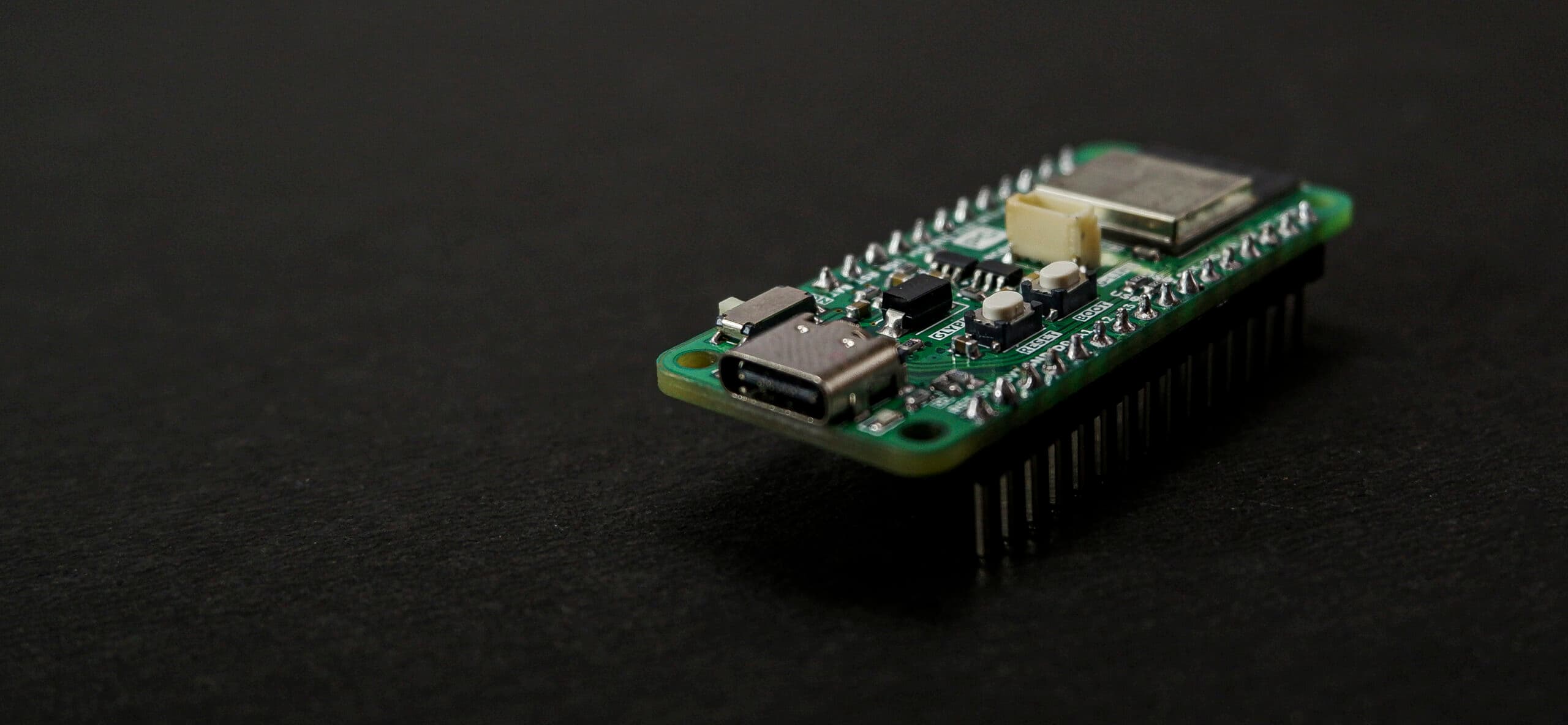 A green microcontroller board with USB-C connector, components and pin headers on a dark surface.