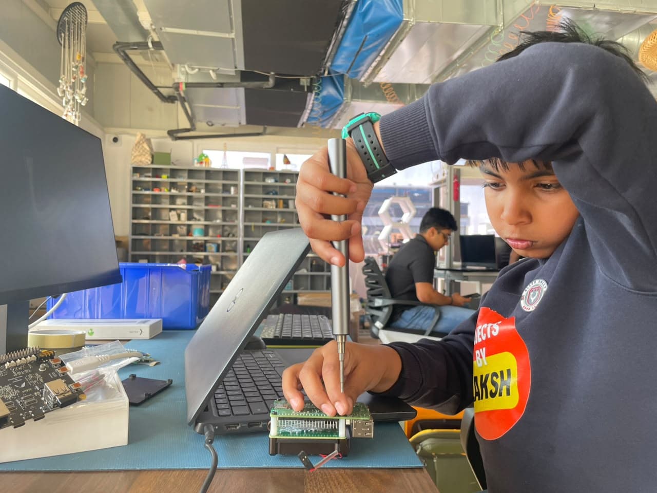 A young builder driving screws into a stacked board assembly at a past event.