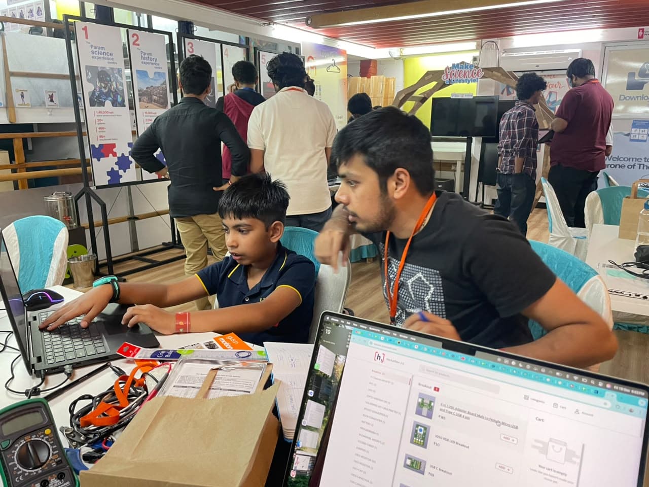 A mentor working alongside a young builder at a past community hardware event.